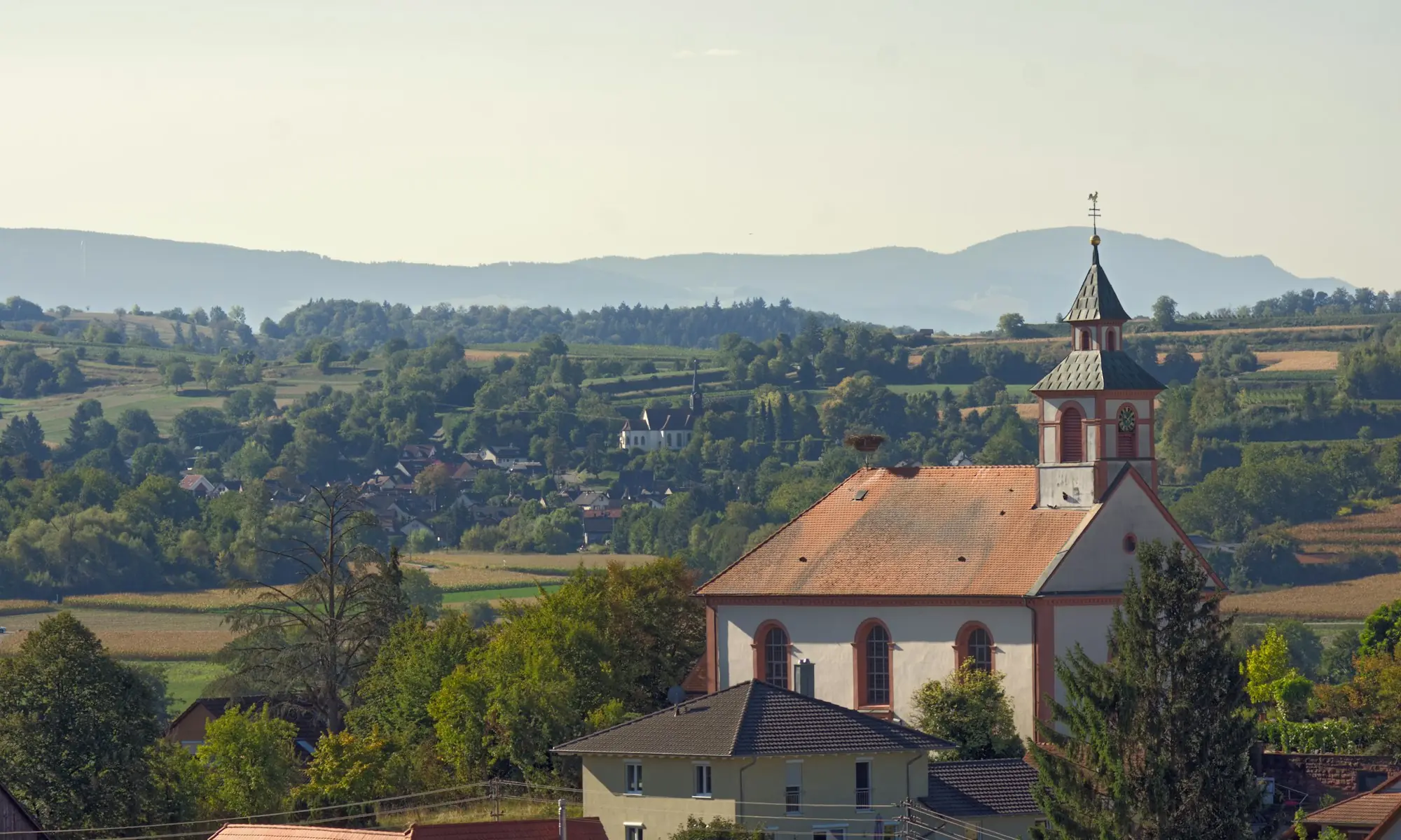 Hügelige Landschaft mit Dorf und Kirche